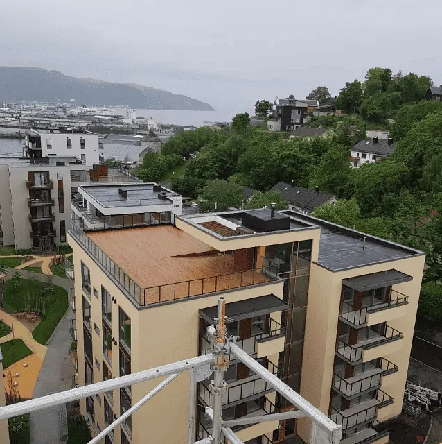 Utsikt over moderne boligblokker, grøntområde og sjø i bakgrunnen.